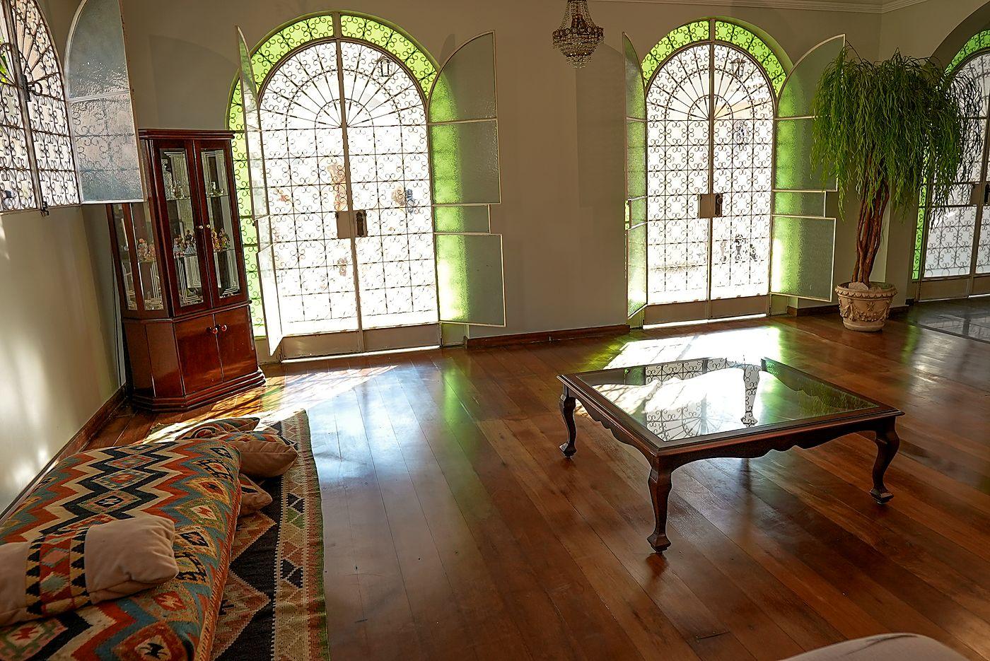 Sala de estar com piso de madeira e portas em arco com vitrais verdes